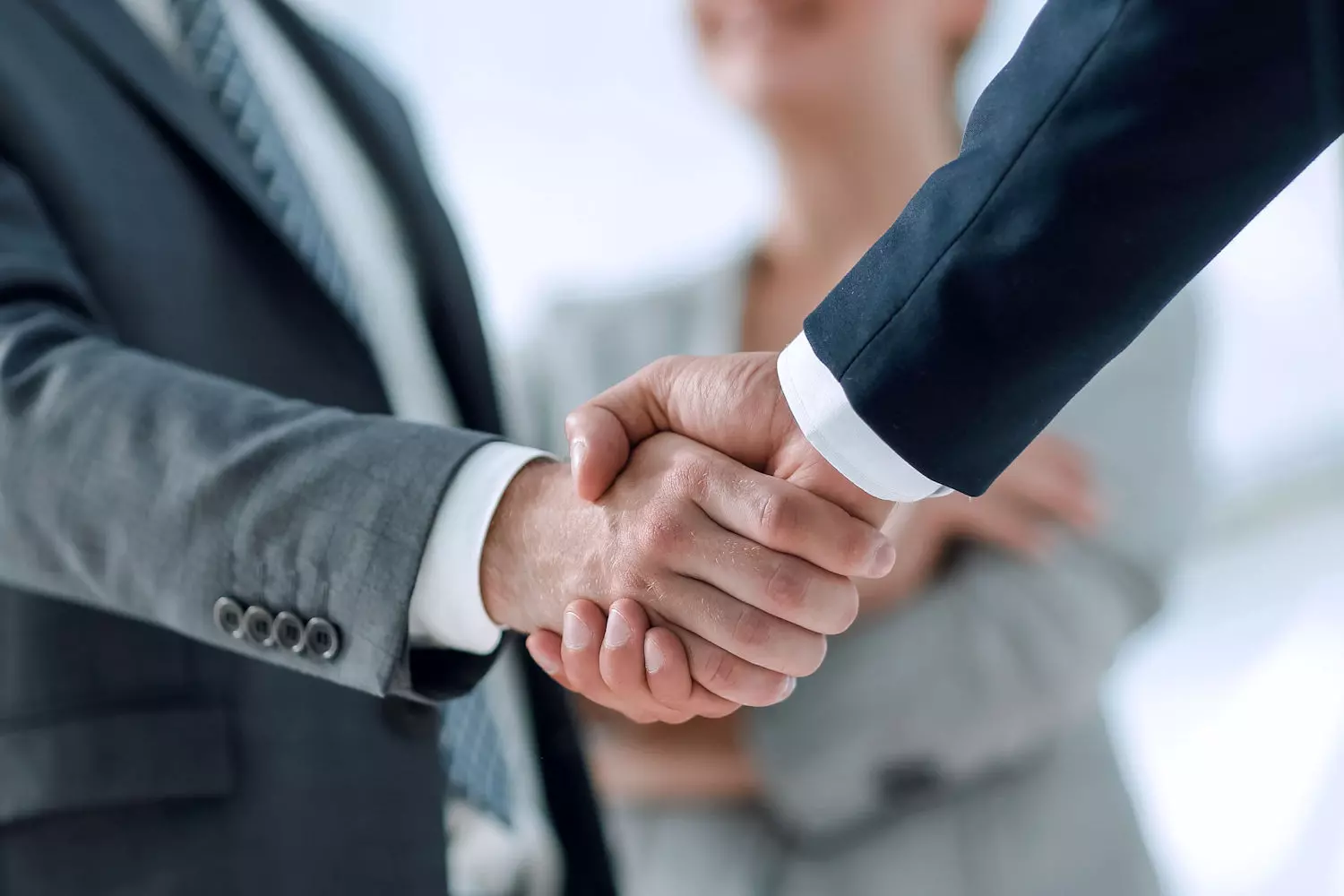 Deux professionnels en costume se serrant la main pour conclure un accord de partenariat.